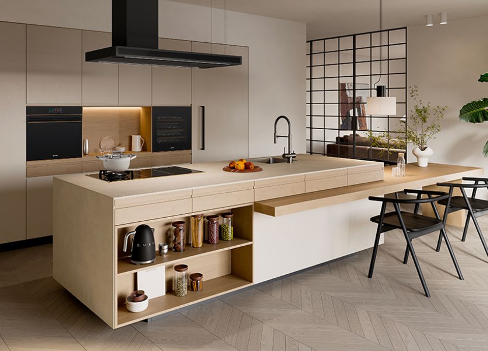 A modern kitchen in light coloured Beech units and pale walls, offset with dark built-in appliances and a centralise island unit with an island cooker hood