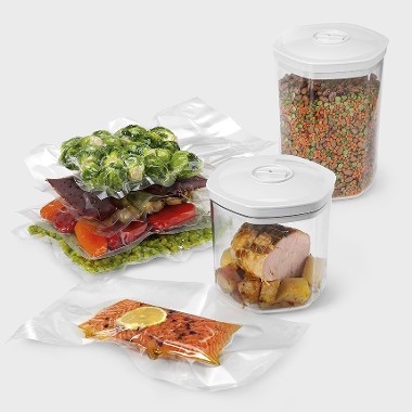 A select of food items such as brussel sprouts, fish, and meat contained within various blast chiller accessories such as clear plastic pots with white lids and clear vacuum packed bags.