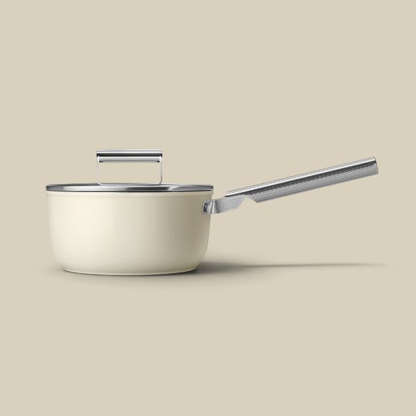 A non-stick cream saucepan with a long stainless steel handle. On top sits a glass lid with a stainless steel handle