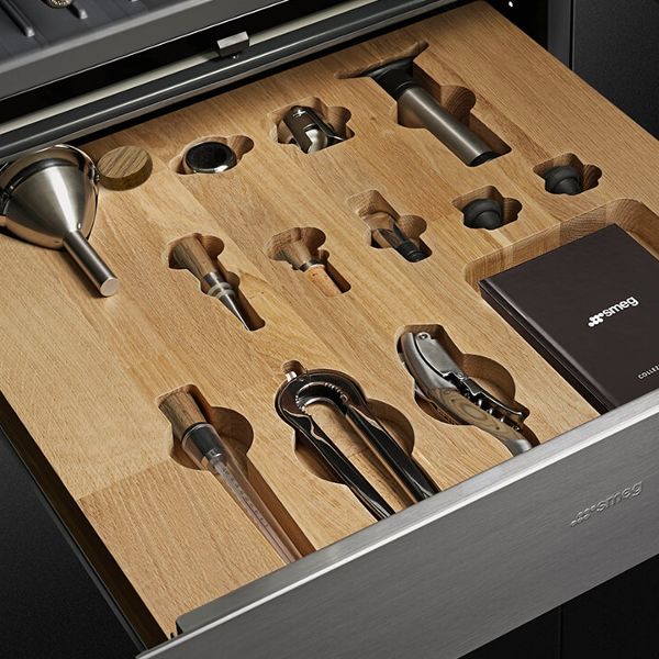 An open sommelier drawer in brushed silver, with wooden insert  with custom placeholders for a selection of wine accoutrements