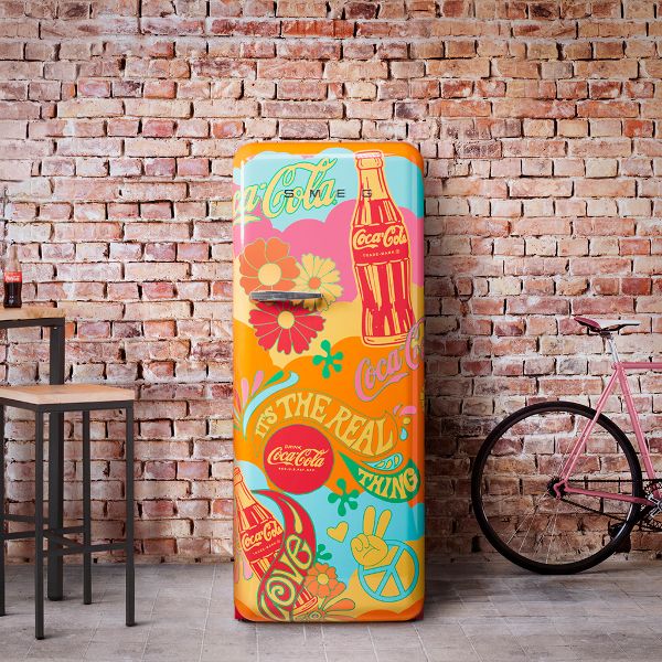 The Coca Cola, limited edition Unity fridge featuring a bold, psychedelic design reminiscent of the 1960's/70s in oranges, yellow, pink and light green. Includes flowers, and peace symbols/signs.
