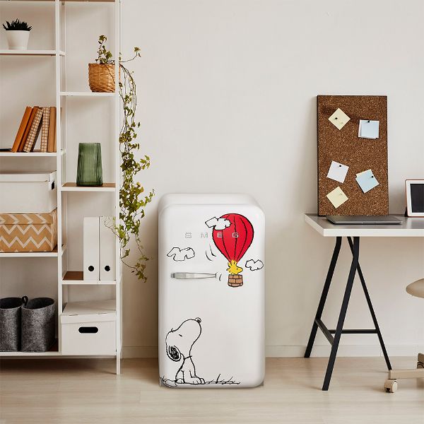 Smeg's Snoopy fridge features a design with Snoopy sitting at the bottom left of the fridge door, looking up towards his best friend Woodstock (a yellow bird) flying away in a red hot hair balloon.