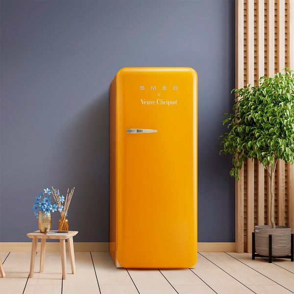 Smeg's designer fridge in the Veuve Clicquot yellow brand colour, set against a blue/grey wall highlighting the striking boldness of colour to create a wow factor.