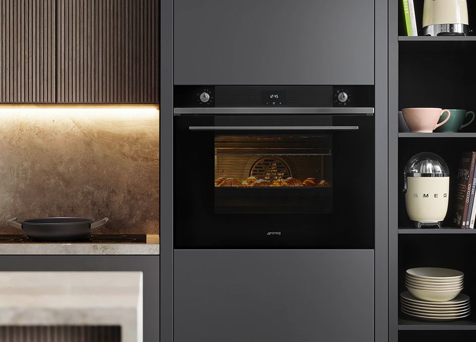 A black single 75 cm oven built into grey kitchen units
