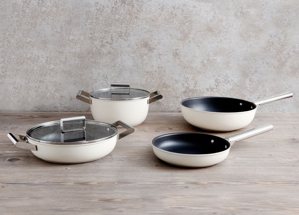 A selection of cream pans, dishes and woks on kitchen worktop