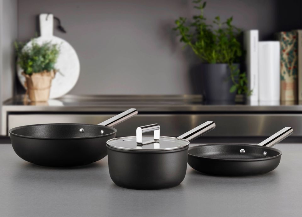A selection of black pans, dishes and woks on kitchen worktop