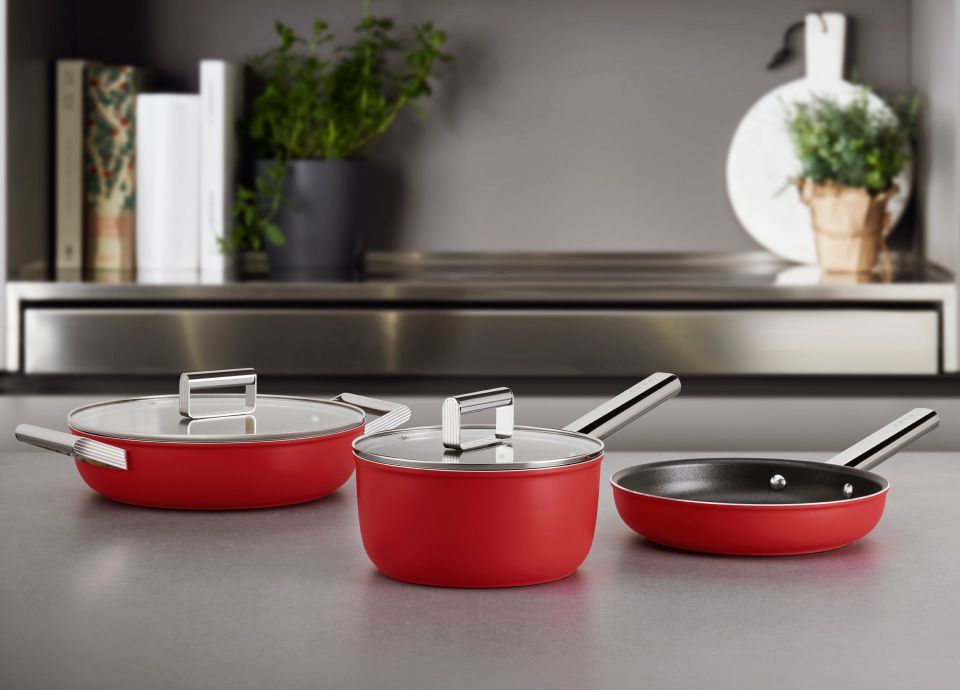 A selection of red pans, dishes and woks on kitchen worktop